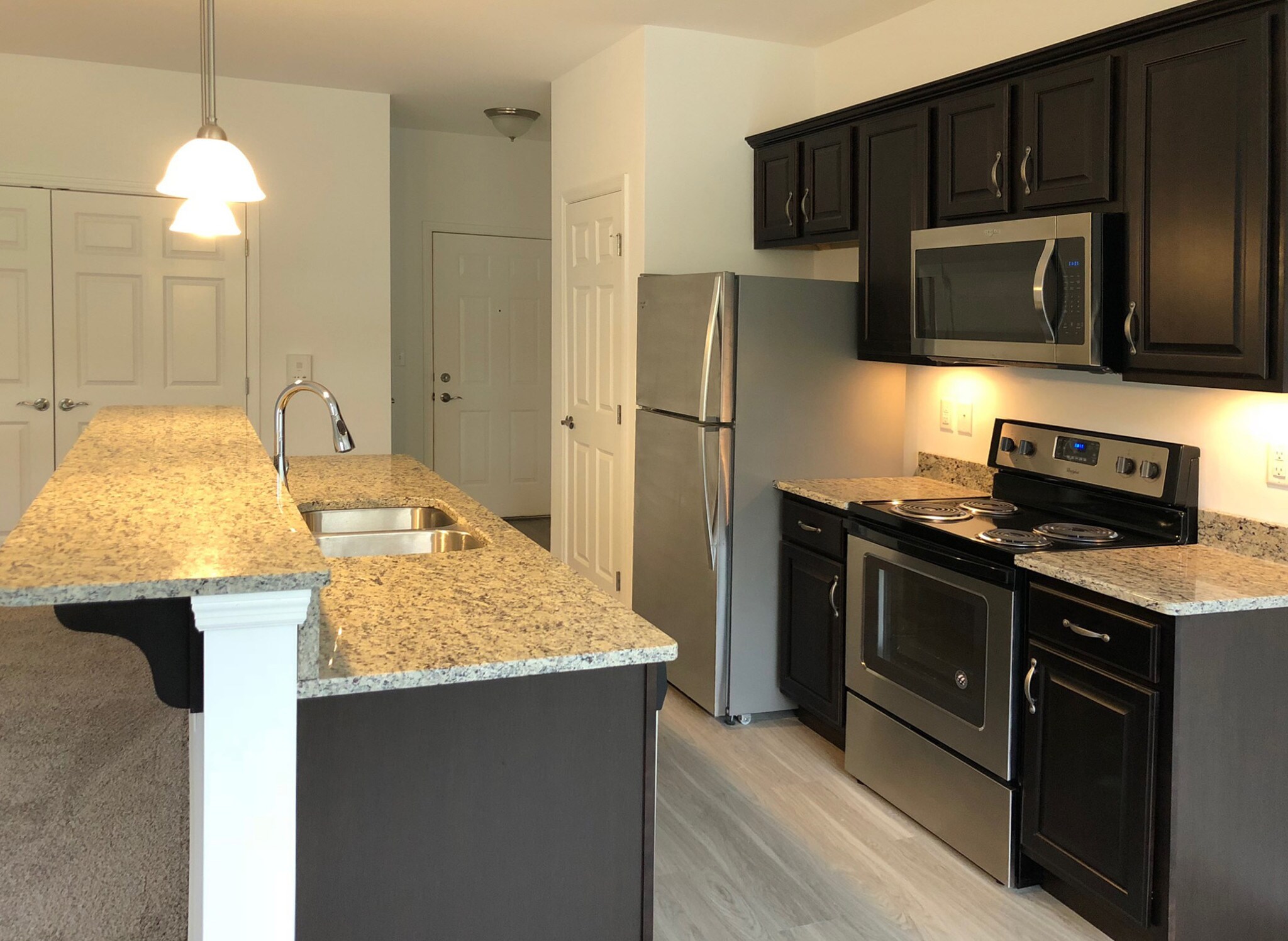 Kitchen with granite breakfast bar, dark cabinetry and stainless steel appliances