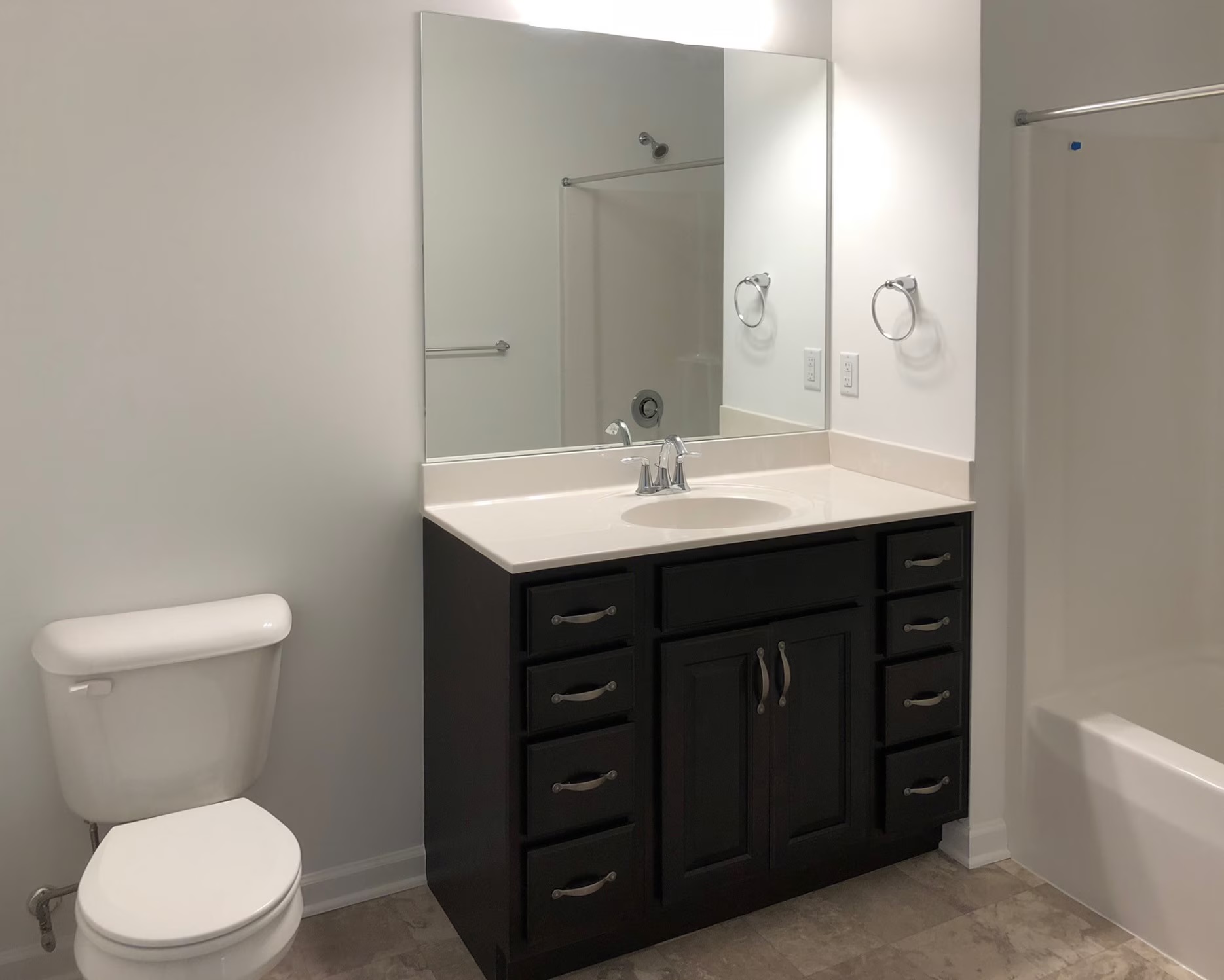 Bathroom with dark wood vanity, large mirror and tub-shower