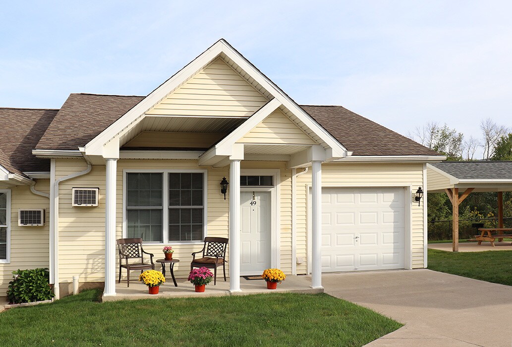 Front porch and attached garage of a Lexington Village home with potted mums